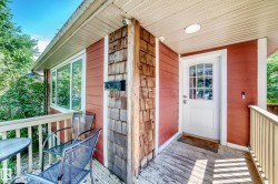 Front porch with wood decking, white railings, and a white paneled door with glass inserts - 