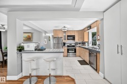 Kitchen featuring wood-finish cabinetry, stainless steel appliances, tile flooring, and a breakfast bar - 