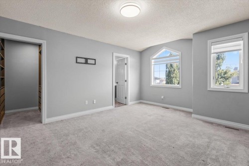 Plush grey carpeting, light grey wall paint, white trim, recessed lighting, and an arched window - 15420 44 Street Nw, Edmonton, AB 