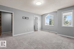 Plush grey carpeting, light grey wall paint, white trim, recessed lighting, and an arched window - 