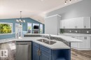 Kitchen island with an undermount dual-basin sink, stainless steel dishwasher, and quartz countertops - 15420 44 Street Nw, Edmonton, AB 