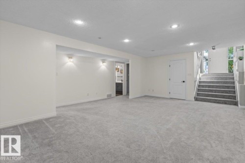 Carpeted lower level with recessed lighting, wall sconces, and interior staircase - 15420 44 Street Nw, Edmonton, AB 