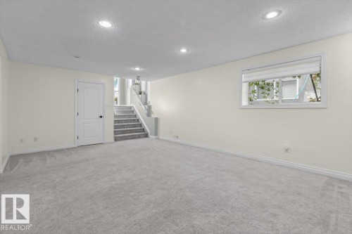Spacious room with light gray carpeting, recessed ceiling lighting, a white interior door, and a multi-pane window - 15420 44 Street Nw, Edmonton, AB 