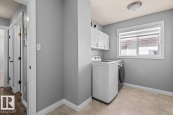 Laundry area featuring white cabinetry, light-colored flooring, and a window for natural light - 