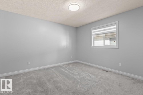 Neutral-toned walls, textured ceiling, window with blinds, and light-toned carpeting - 15420 44 Street Nw, Edmonton, AB 