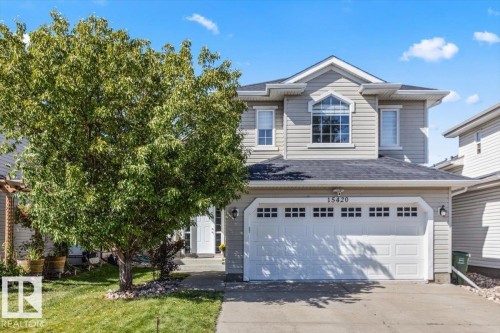 Two-story property with light-colored siding, a two-car garage, and a prominent arched window on the upper level - 15420 44 Street Nw, Edmonton, AB 
