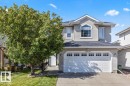 Two-story property with light-colored siding, a two-car garage, and a prominent arched window on the upper level - 15420 44 Street Nw, Edmonton, AB 