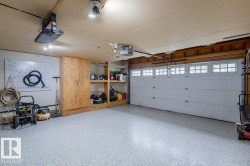 Garage featuring a white segmented door with transom windows, built-in wooden shelving, and a light-toned finished floor - 