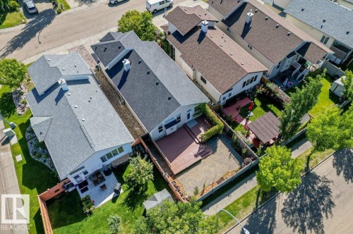 Rear yard featuring a wood-finish deck, paved patio area, and mature perimeter trees - 15420 44 Street Nw, Edmonton, AB 