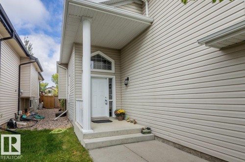 Front entry featuring a transom window, sidelight, and covered porch with a column - 15420 44 Street Nw, Edmonton, AB 