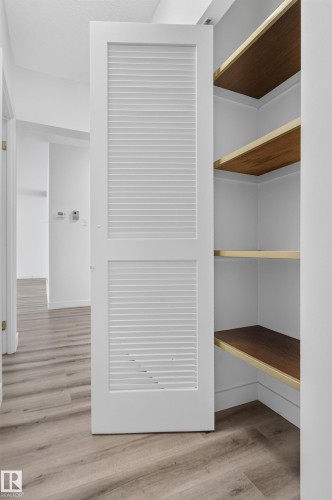 White louvered bifold door, wood-finish shelving, and wood-finish flooring - #301 9809 110 St Nw, Edmonton, AB 