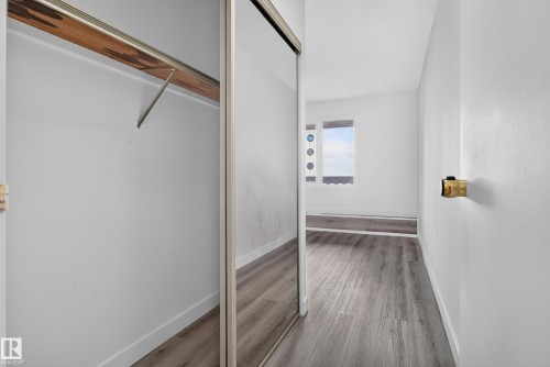 Mirrored closet doors, wood-finish flooring, and a window with decorative circular accents - #301 9809 110 St Nw, Edmonton, AB 