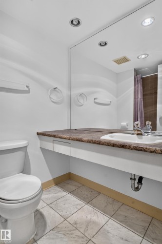 Recessed lighting illuminates a built-in vanity with an integrated sink and a brown-toned countertop - #301 9809 110 St Nw, Edmonton, AB 
