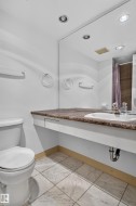 Recessed lighting illuminates a built-in vanity with an integrated sink and a brown-toned countertop - 