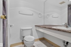 White toilet with a built-in shelf, vanity with integrated sink, and a large wall-mounted mirror - 