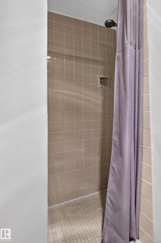 Tiled shower enclosure with a built-in soap dish and a dark-finish shower head - #301 9809 110 St Nw, Edmonton, AB 
