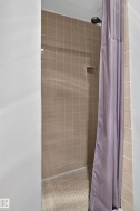 Tiled shower enclosure with a built-in soap dish and a dark-finish shower head - 