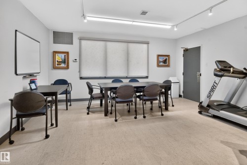 Room with track lighting, multiple windows with roller shades, and light-toned flooring - #301 9809 110 St Nw, Edmonton, AB 