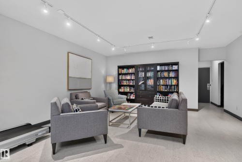 Recessed track lighting illuminates this versatile space featuring a built-in dark wood-finish cabinet with glass doors and light-tone flooring - #301 9809 110 St Nw, Edmonton, AB 