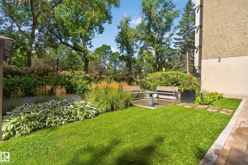 Landscaped outdoor area featuring a manicured lawn, paver patio, and mature trees - #301 9809 110 St Nw, Edmonton, AB 