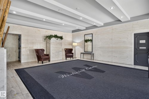 Recessed lighting illuminates the entrance, highlighting architectural wall panels, durable tile flooring, and a decorative ceiling design - #301 9809 110 St Nw, Edmonton, AB 