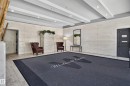 Recessed lighting illuminates the entrance, highlighting architectural wall panels, durable tile flooring, and a decorative ceiling design - #301 9809 110 St Nw, Edmonton, AB 