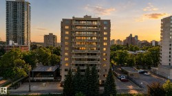Multi-story building featuring numerous balconies and a visible parking area - 