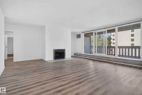 Wood-finish flooring, white walls, built-in fireplace, and expansive sliding glass doors - #301 9809 110 St Nw, Edmonton, AB 