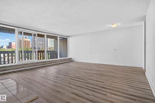 Expansive wood-finish flooring, white walls, and a built-in flush-mount ceiling light - #301 9809 110 St Nw, Edmonton, AB 