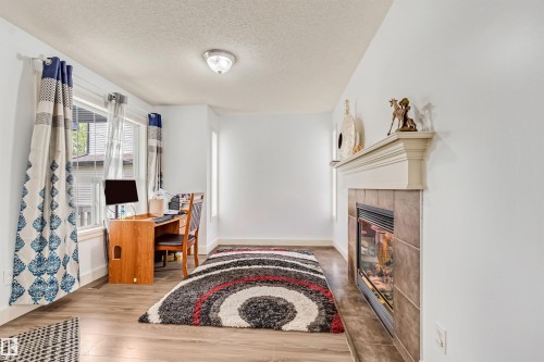 Recessed fireplace with tile surround and mantel, wood-finish flooring, and multiple windows providing natural light - 20324 48 Avenue Nw, Edmonton, AB 