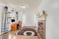 Recessed fireplace with tile surround and mantel, wood-finish flooring, and multiple windows providing natural light - 