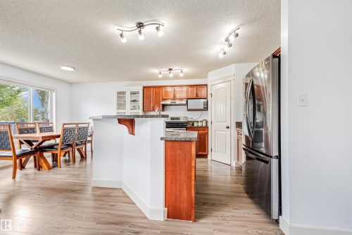Wood-finish flooring, white walls, and a kitchen island with stone countertops - 20324 48 Avenue Nw, Edmonton, AB 