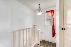 Staircase with light wood-finish flooring, white spindle railing, and a window providing natural illumination - 