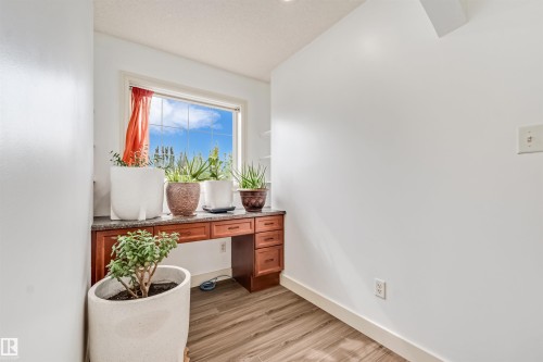 Built-in desk with wood-finish cabinetry, stone countertop, and wood-finish flooring - 20324 48 Avenue Nw, Edmonton, AB 