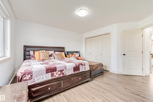 Light wood-finish flooring, white walls, double bi-fold closet doors, and an overhead flush-mount light fixture - 20324 48 Avenue Nw, Edmonton, AB 
