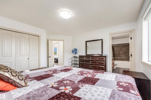 White interior walls, overhead light fixture, dual pane window, white six-panel closet doors, and dark wood-finish flooring in the bathroom - 20324 48 Avenue Nw, Edmonton, AB 