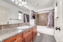 Vanity with a single basin sink, wood-finish cabinetry, and a stone-look countertop - 