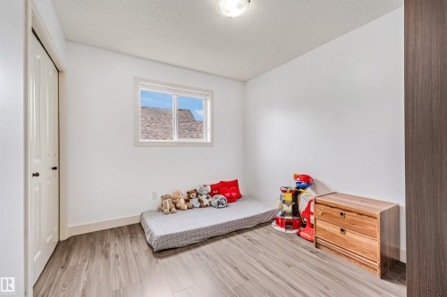 White walls with wood-finish flooring, a white window, and a white bi-fold closet door - 20324 48 Avenue Nw, Edmonton, AB 