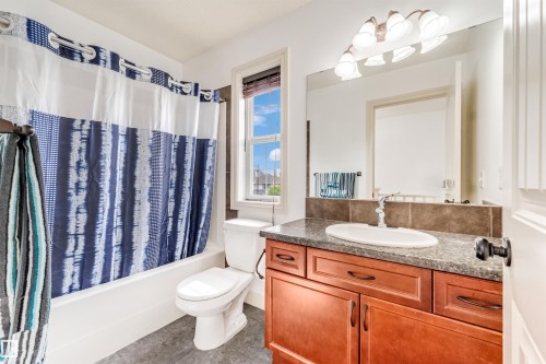 Full vanity with a granite-style countertop, undermount sink, and wood-finish cabinetry - 20324 48 Avenue Nw, Edmonton, AB 