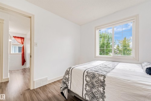 White painted walls, wood-finish flooring, and a large window with grid panes - 20324 48 Avenue Nw, Edmonton, AB 