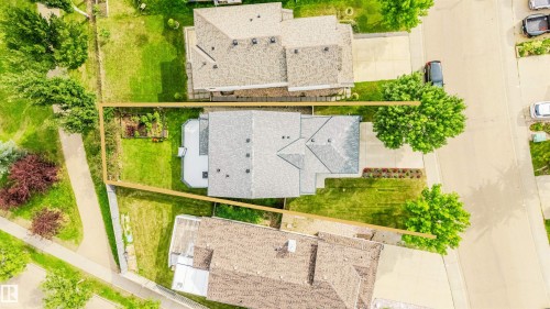 Expansive lot featuring a residential structure with a shingled roof, surrounding green spaces, and mature trees - 20324 48 Avenue Nw, Edmonton, AB 