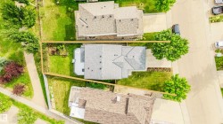Expansive lot featuring a residential structure with a shingled roof, surrounding green spaces, and mature trees - 