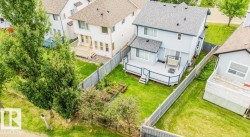 Spacious backyard featuring a multi-level deck with white railings, a manicured lawn, and mature trees - 