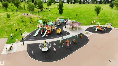 Expansive green space featuring multiple play structures, a covered picnic area, and paved pathways - 20324 48 Avenue Nw, Edmonton, AB 