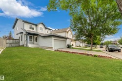 Two-story exterior with light-toned siding, attached garage, front lawn, and paved driveway - 