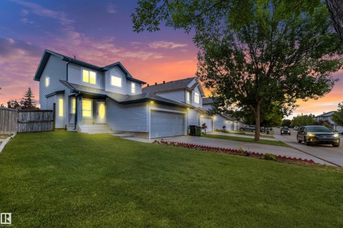 Two-story exterior with light blue siding, an attached garage, a front lawn, and a paved driveway - 20324 48 Avenue Nw, Edmonton, AB 