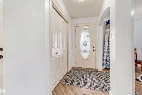 Entryway featuring a decorative oval glass door, wood-finish flooring, and built-in bi-fold closet doors - 20324 48 Avenue Nw, Edmonton, AB 