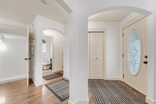 Entryway featuring wood-finish flooring, an arched doorway, and a front door with decorative glass - 20324 48 Avenue Nw, Edmonton, AB 
