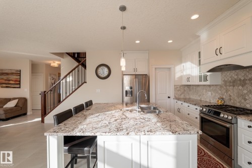 Kitchen featuring white cabinetry, stainless steel appliances, granite countertops, and a tiled backsplash - 914 Crystallina Nera Way Nw, Edmonton, AB 