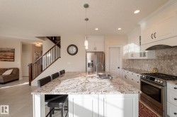 Kitchen featuring white cabinetry, stainless steel appliances, granite countertops, and a tiled backsplash - 